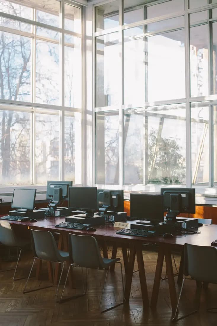 Computer workstations in a bright glass-walled study room